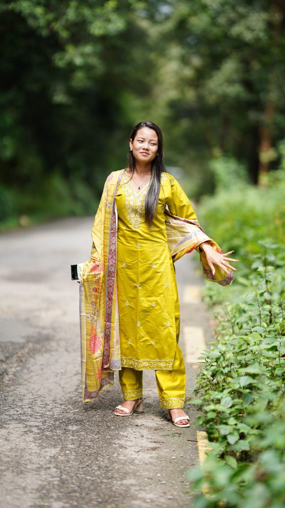 Young woman wearing vibrant ethnic attire poses on a scenic outdoor path.